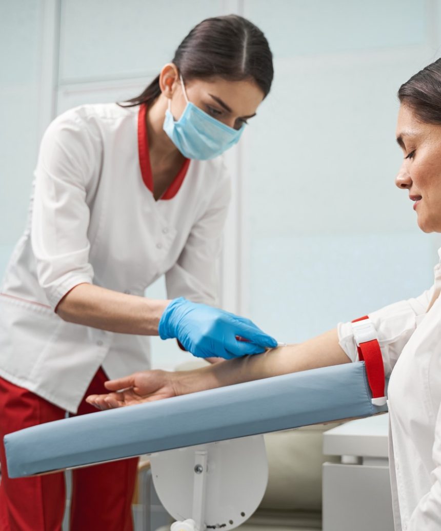 Do it quickly. Beautiful longhaired brunette sitting in semi position and giving her arm for blood sampling